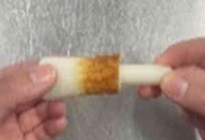 竹笛を半分に切り、ちくわの穴にトッポギ用もちを入れます。